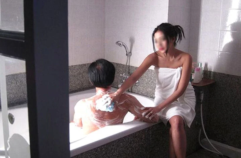 een aziatisch meisje dat de rug scrubd van een man met zeep
